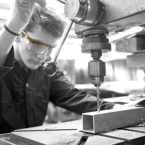 Visuel illustration : un jeune devant une perceuse industrielle